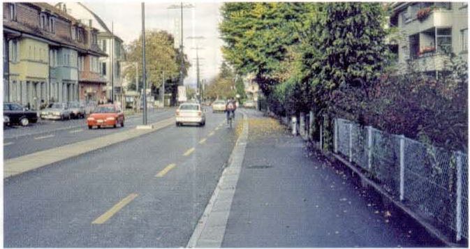Районная улица на въезде с разделительной полосой, по которой возможен проезд, и выделенной велосипедной полосой